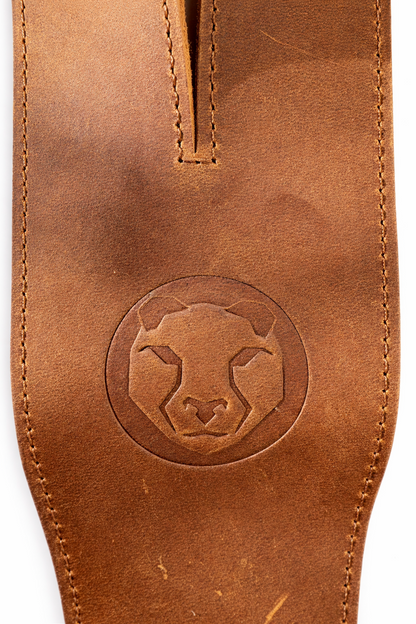 Brown leather lifting strap with a circular embossed design on a white background